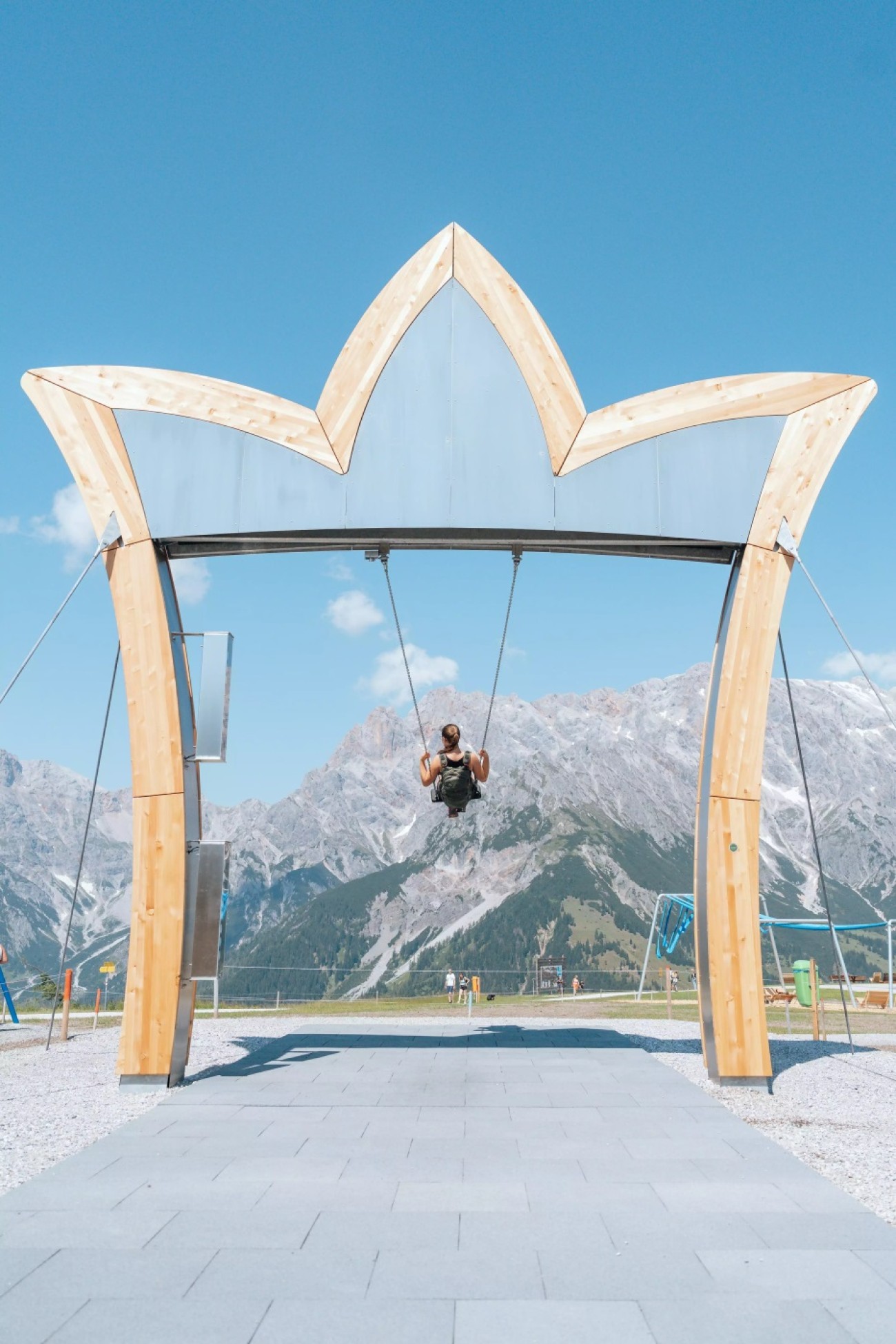 Person schaukelt unter hölzerner Krone vor malerischem Bergpanorama von Hochkönig. ©TVB_Hochkönig