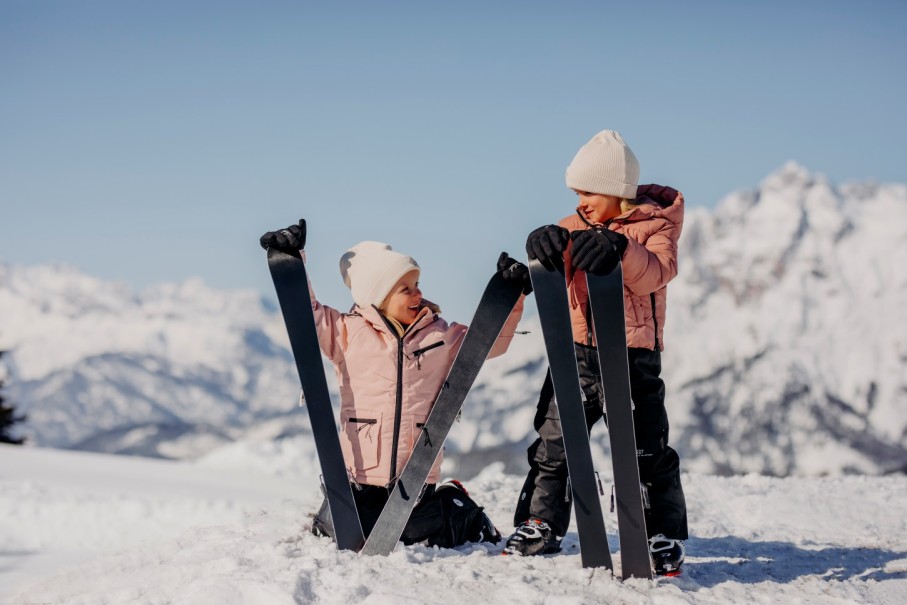 Kinder posieren mit Skiern im verschneiten Hochkönig, Skiurlaub und Familienmomente. ©SalzburgerLand Tourismus-Verena Schierl