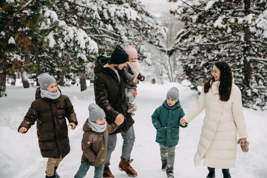 Eine Familie spaziert fröhlich im verschneiten Wald im Familienurlaub im Salzburger Land. © Shutterstock